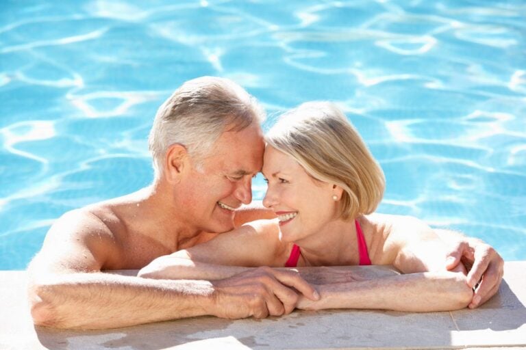 Older couple relaxing at the edge of a swimming pool