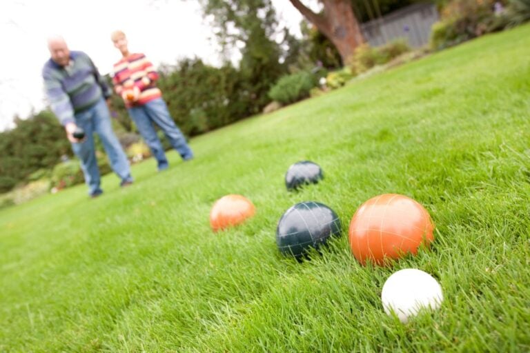 Older friends playing bocce on a lawn