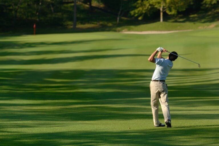 Golfer swinging on a green fairway